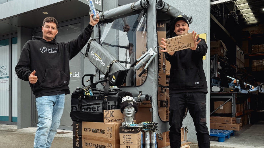 Two men standing with a large piece of equipment and boxes in front of a building with 'Digger Ltd' signage.