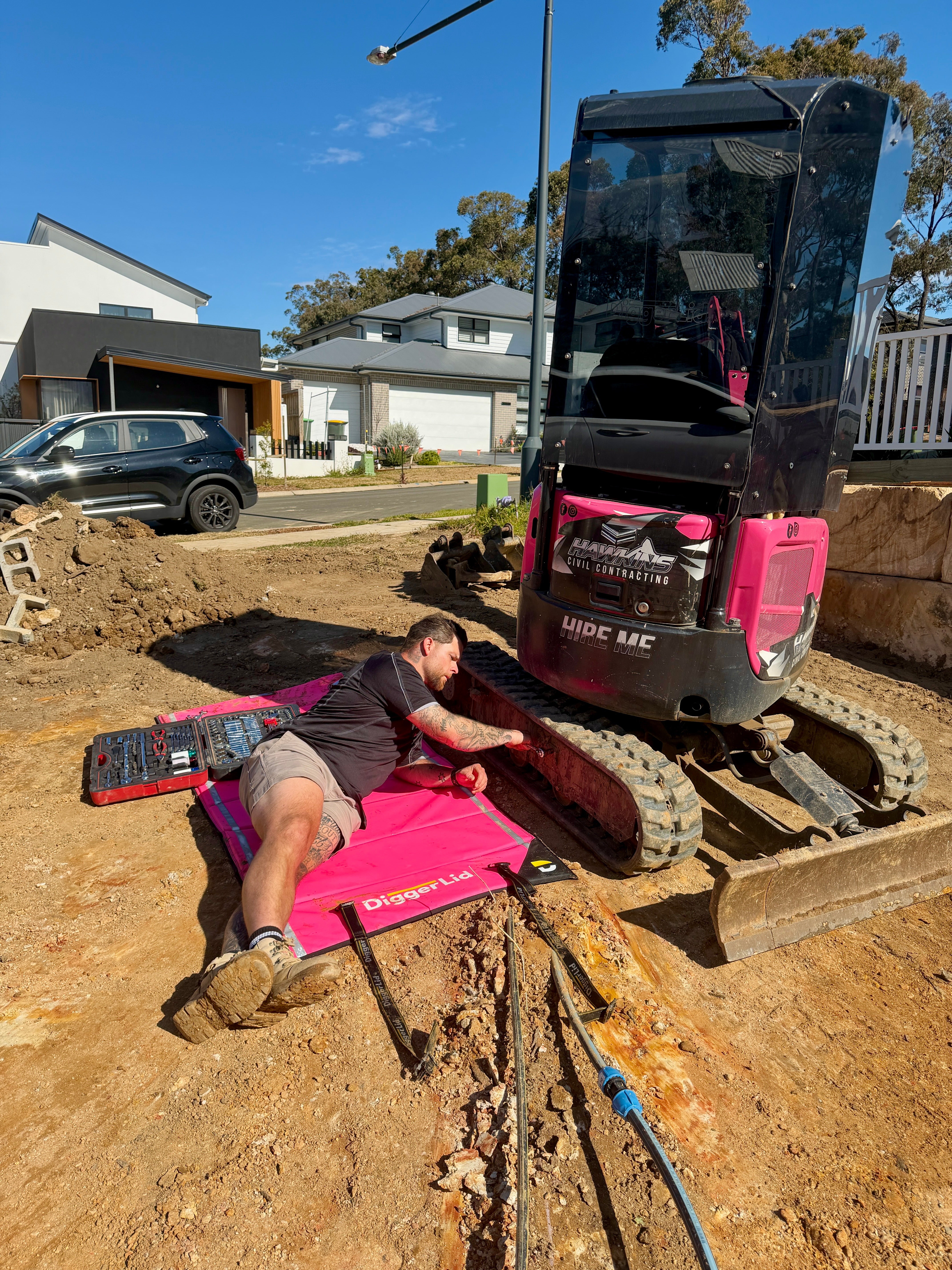 Operator working on a pink mini excavator over a Safety Pink Pro Mat Plus