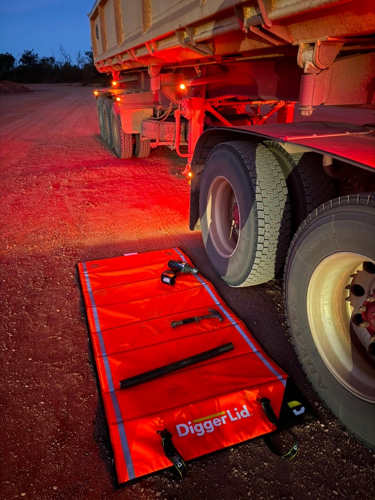 Safety Orange Pro Mat Plus with tools laid out at night beside a tipper trailer